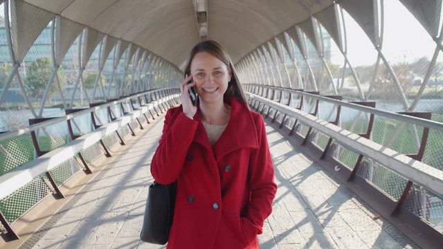 Beautiful woman walking in the city and talking by cell phone
