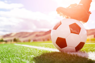 Soccer ball with player foot on soccer field