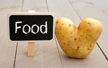 Food chalkboard with heart shaped potato on wooden background