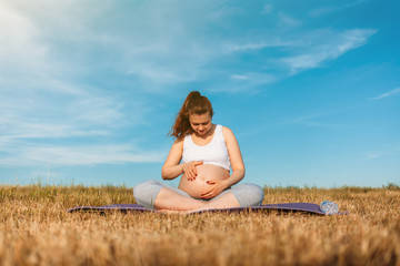 Fototapeta na wymiar Pregnant woman exercising yoga on the mat