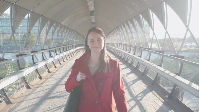 Beautiful woman walking in the city and looking at camera smiling.