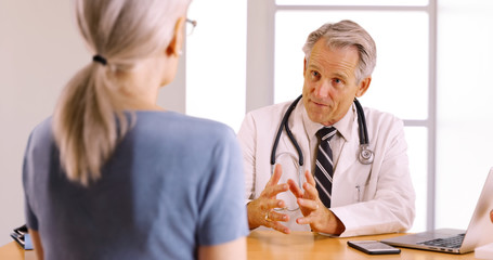 Senior doctor discussing surgery procedure with elderly woman patient