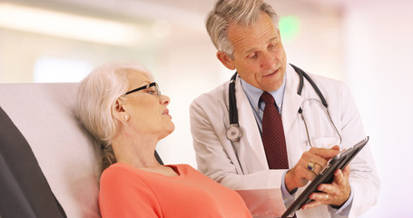 Successful doctor talking with elderly woman patient in the office