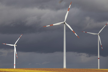 Three wind turbines in the field on dark gloomy day