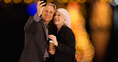 Elderly couple using smartphone to take selfies with the view