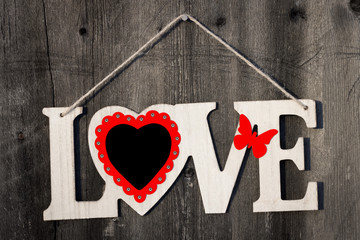 Cut out from plywood the word love hanging on a dark wooden background