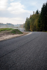 Fototapeta na wymiar misty countryside landscape with asphalt wavy road in latvia