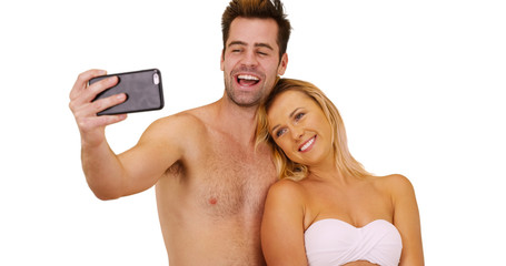 Fototapeta na wymiar Happy millennial couple taking pictures with smartphone at the beach