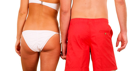 Rear view of young couple wearing swim suits and standing in front of white background