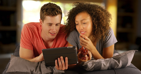 Couple of multiracial friends using tablet handheld device.
