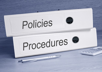 Policies and Procedures binder in the Office with pen and calculator