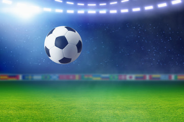 Soccer ball, bright spotlight illuminates green football field