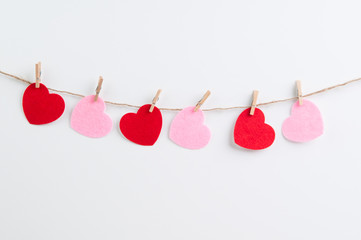 Pink and red flet hearts pinned to a line of twine with mini clothes pegs. © sianc
