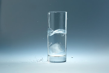 ice cube falls in a glass of water