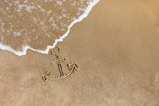 Anchor drawn on the beach sand. Summer holidays background
