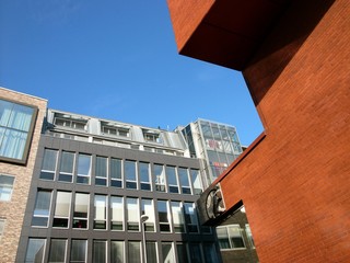 Moderne Bürogebäude mit Klinkerfassade und viel Glas vor blauem Himmel im Sonnenschein am...