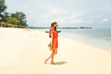 girl in hat holding pineapple on the beach