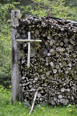 kleines holzkreuz an einem holzstapel