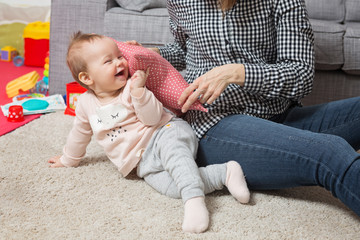 Nine months old baby girl playing with her mother on the floor