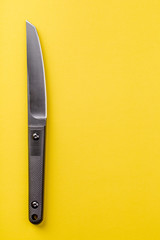 Black knife on yellow background. survival and bushcraft concept