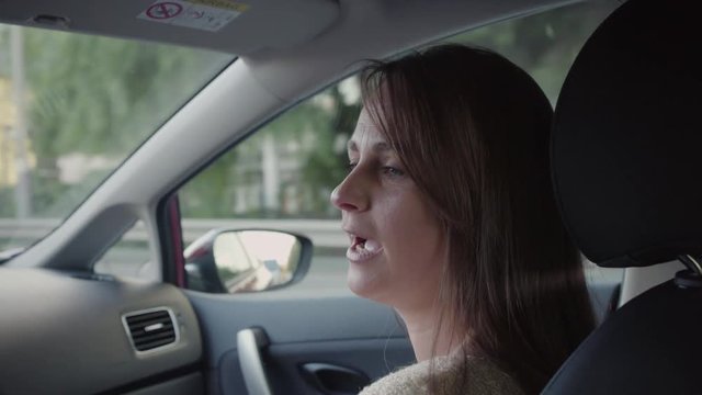 Beautiful woman travels by car. She smiles and talks with the driver.