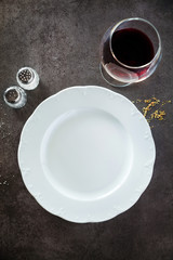 Obraz na płótnie Canvas Empty Plate and Red Wine glass on a dark restaurant or bar count