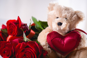 Valentines teddy bear with roses on bright background on wooden