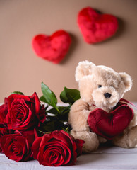 Valentines teddy bear with roses on bright background on wooden