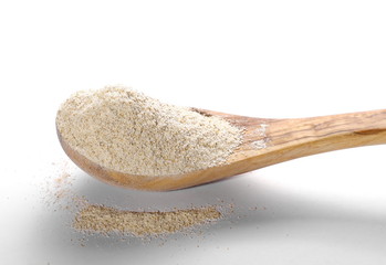 pile whole grain barley flour and wooden spoon isolated on white background