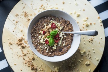 Chocolatiers breakfast   with oatmeal, puffed rice, cereals , dried strawberries   prepared in a white bowl.  