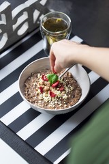 Breakfast with  chocolate oatmeal prepared by a woman, puffed rice, cereals , dried strawberries in white bowl and  green tea 