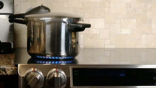 Stainless Steel Pressure Cooker Letting Off Steam On A Modern Induction Cooking Hob With Glass Top