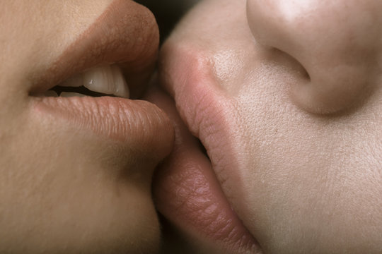 Lesbian sexy lovers kissing, foreplay. Closeup of pair women mouths kissing. Sensual lips kisses of two beautiful sexy lesbian women on a dark background. Lesbian Couple Together Indoors Concept