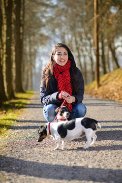 People and dogs outdoors. Beautiful and happy woman enjoying in autumn park walking with her Jack Russell terrier..Colored photo