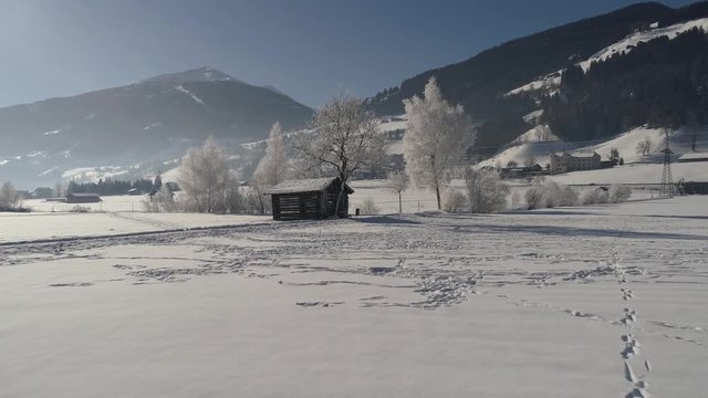 Barn in the snow-covered field. Flying on drone