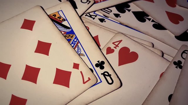 Various playing cards rotate on table. Macro shot.