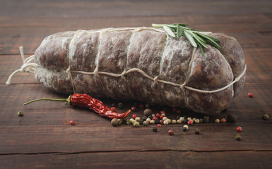 Italian salami with red pepper and rosemary on a wooden background