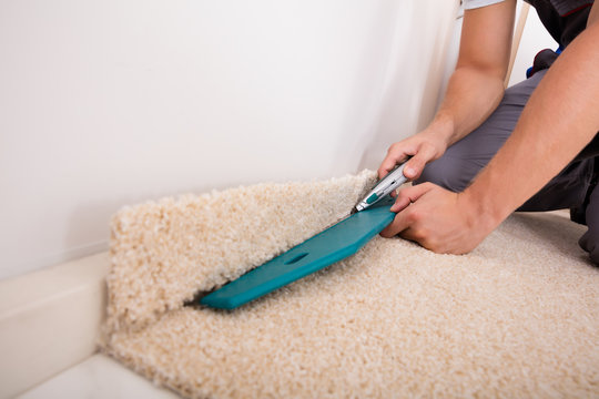 Person Cutting Carpet With Cutter
