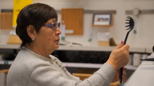 woman chooses kitchen ladles in shop.