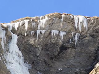 Fototapeta na wymiar Ice stalactites and frozen waterfall on a rock face