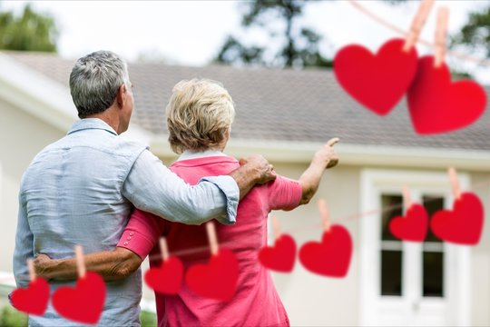 Senior couple pointing towards house