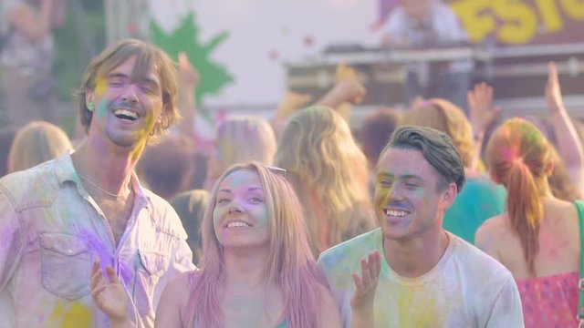 Three happy friends dancing at open air Color festival , enjoying life, slow-mo