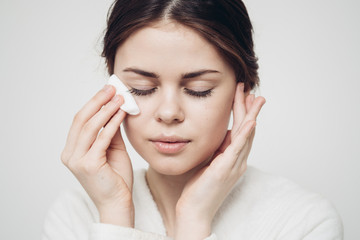 woman wipes her face with a cotton pad, tender skin