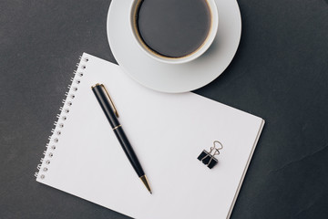 a cup of tea on the table and a pen with a clip on a notebook