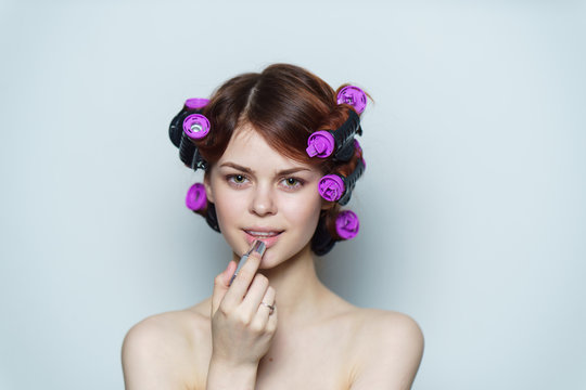 woman in purple hair curlers paints lips