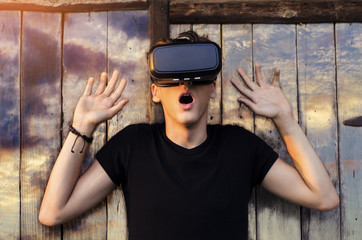 Teenager amazed with VR glasses, photo manipulation, sky background on wooden doors