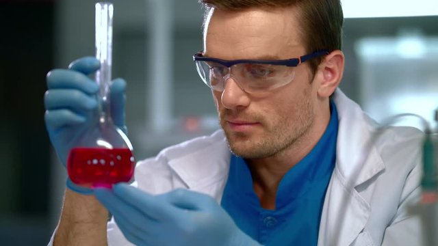 Chemist in lab. Close up of chemist doing chemical research at chemical laboratory. Chemical engineering. Chemist doing chemical test. Chemist working with liquid at glass flask at chemistry lab