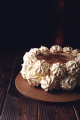 White Meringue cake, sprinkled with cocoa on a wooden table
