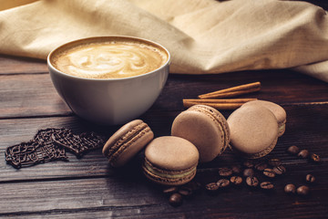 Coffee with macarons and chocolate in the shape of heart.