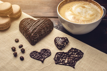 Coffee cappuccino with beautiful foam next macarons and chocolate heart.